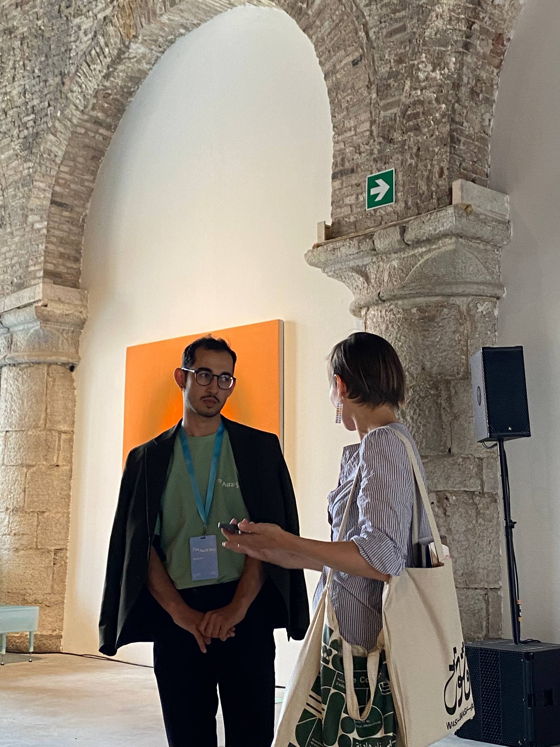 Conversation in front of an orange canvas in a stone gallery