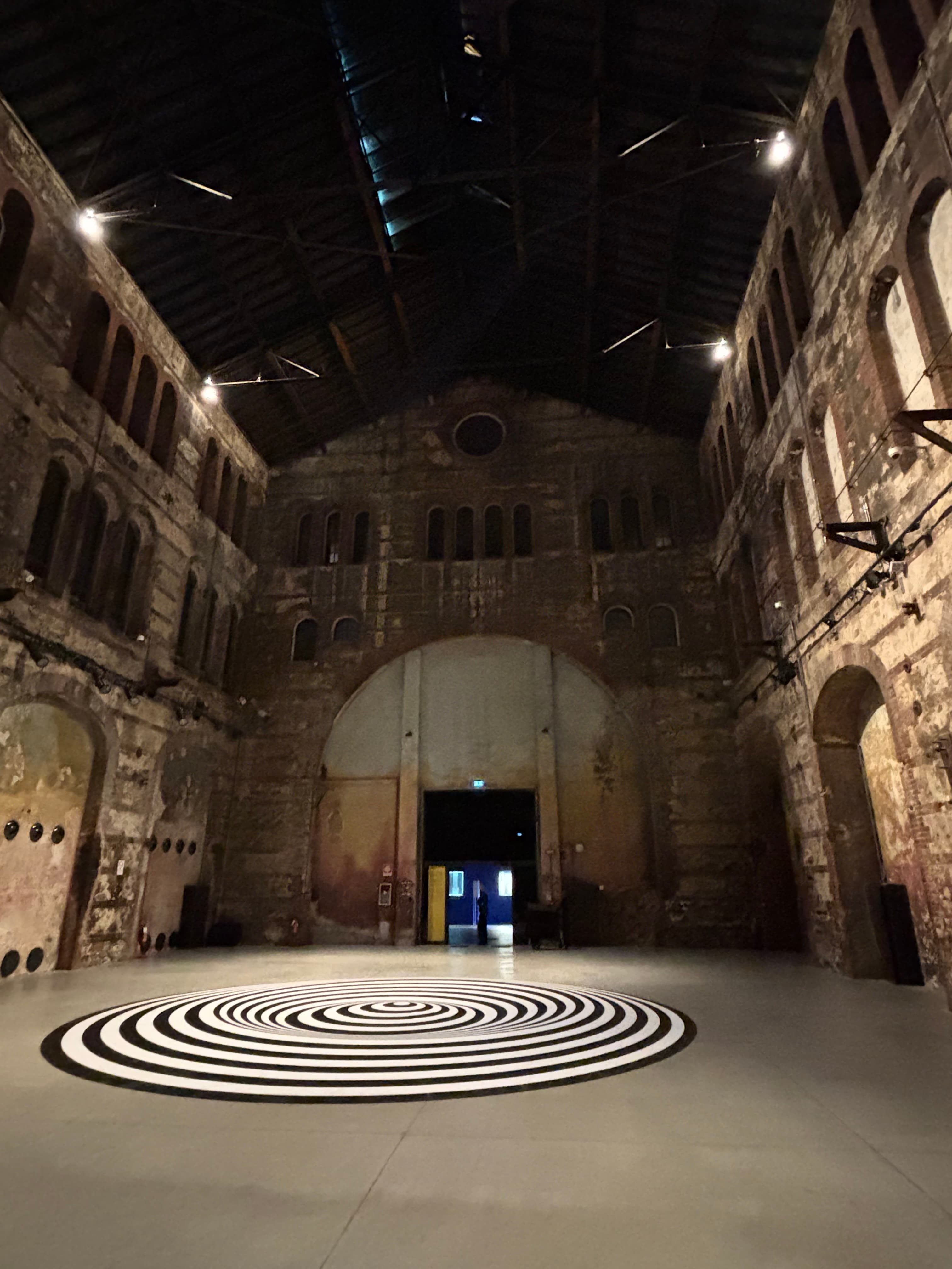 Vast industrial hall with an op-art floor piece