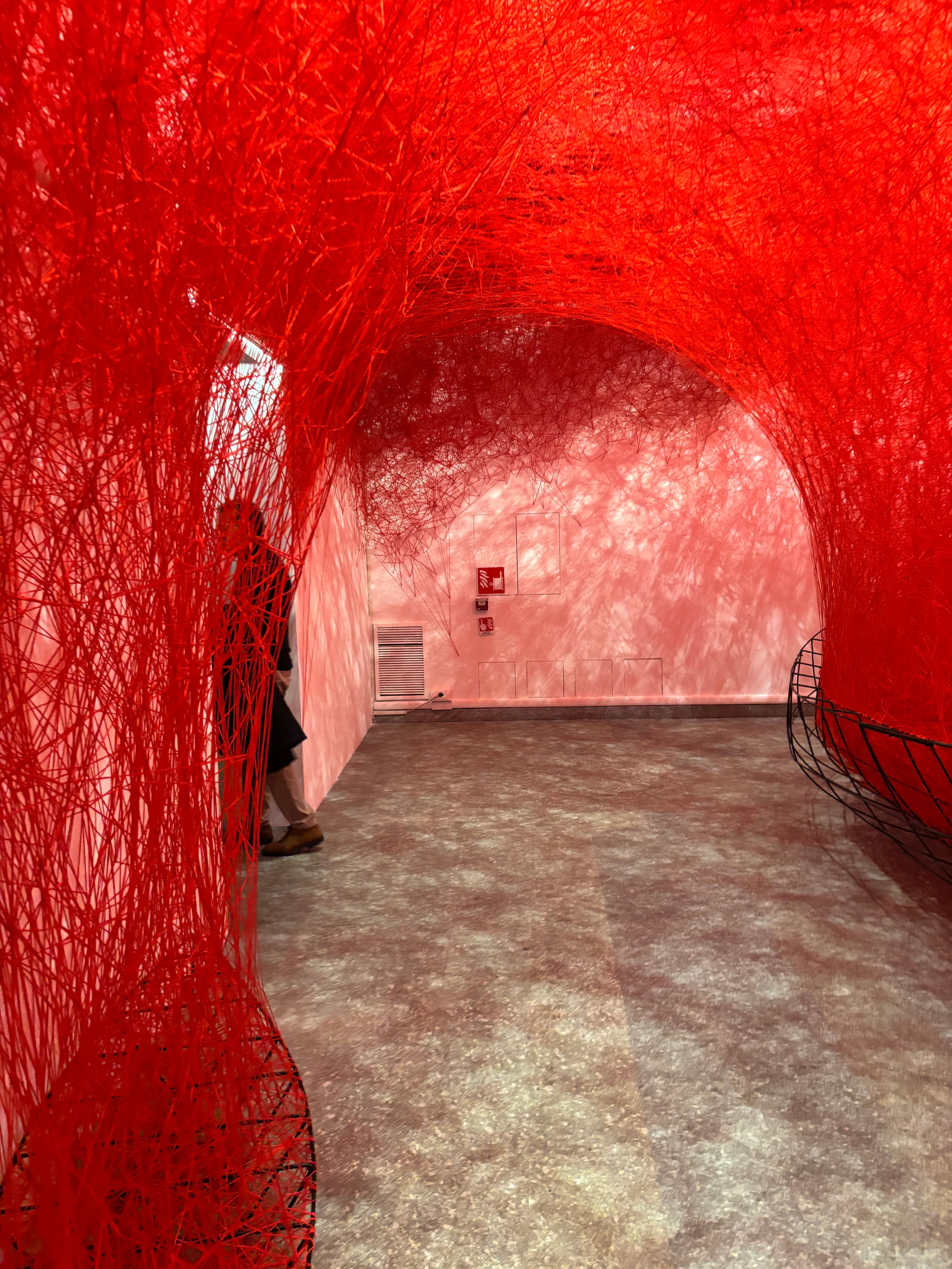 Red thread installation enveloping a gallery room